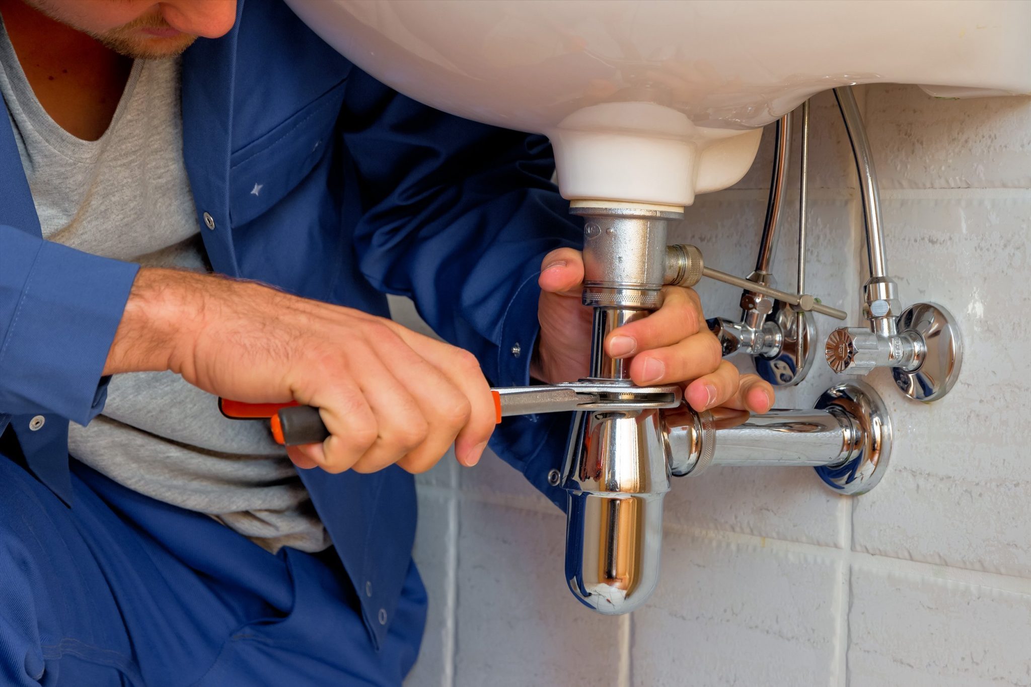 A plumber fixing a pipe with a tool | General Plumbing Services
