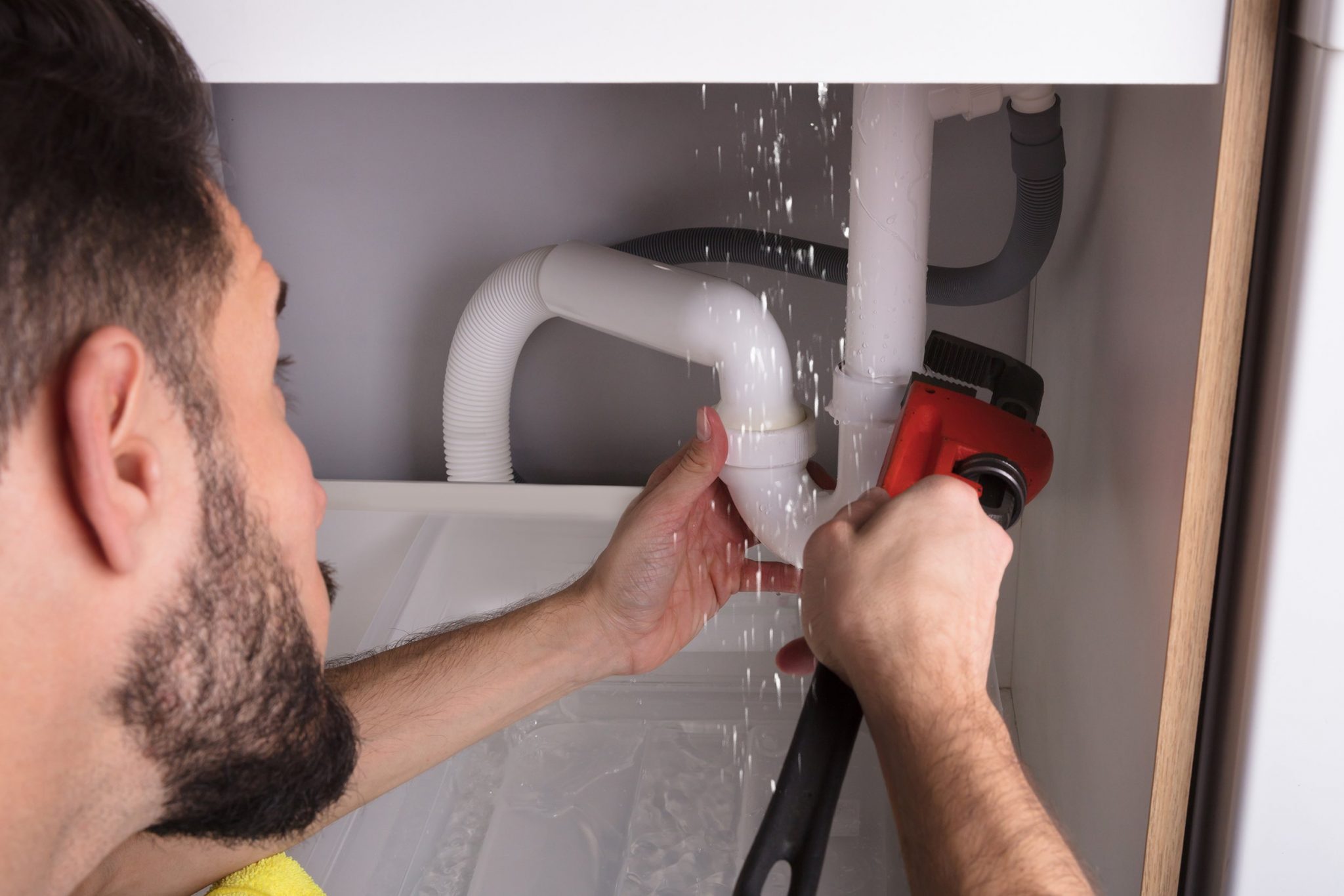 A plumber fixing a leaking pipe| Drain Cleaning Ocala FL